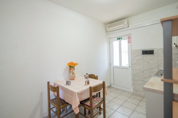 A small dining area with a table set for two, a vase with flowers, and a door with an exit sign. - Apartments Pinija - (Supetar)