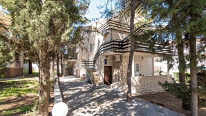 A stone building with a staircase leading to a balcony, surrounded by trees. - Apartments Pinija - (Supetar)