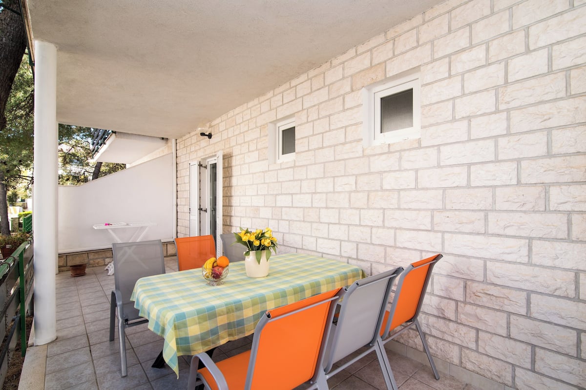 Un patio con una mesa y sillas, un florero con flores y un muro de ladrillo.