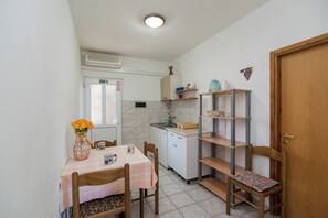 A small kitchen with a dining table, chairs, a sink, and a cabinet. - Apartments Pinija - (Supetar)