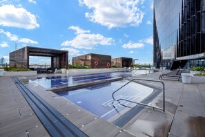 A rooftop pool with a clear view of the city skyline, modern buildings, and a covered seating area.