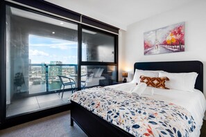 Una camera da letto con un letto grande, vista sulla città e un balcone con porta vetrata.