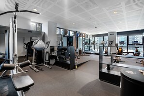 Una palestra moderna con diverse attrezzature per l'allenamento, ampie finestre e un soffitto alto.