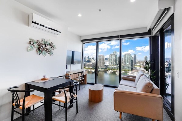 A modern living room with a city view, a dining area, and a sofa.