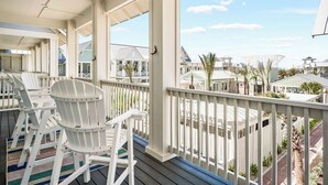 Un espace extérieur abrité, doté de chaises Adirondack blanches et offrant une vue sur les maisons voisines.