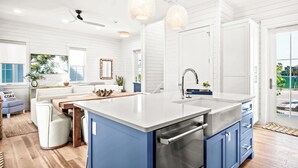 Une cuisine moderne dotée d’un grand îlot central, de meubles blancs et de touches de couleur bleue.