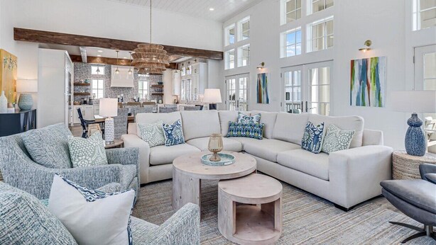 A spacious living room with a large white sectional sofa, a round coffee table, and a kitchen in the background. - Premier Beach Home@Cinnamon Shore North w/ Private Pool, Fire Pit & More! (Port Aransas)