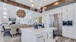 A modern kitchen with white cabinetry, stainless steel appliances, and a central island. - Premier Beach Home@Cinnamon Shore North w/ Private Pool, Fire Pit & More! (Port Aransas)