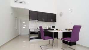 A modern kitchen with dark cabinets, a white countertop, and two purple chairs. - LUV Luxury Apartments (Dubrovnik)