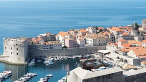 A coastal town with historic buildings, a fortified castle, and a marina with boats. - LUV Luxury Apartments (Dubrovnik)