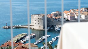 A coastal town with a historic fort, a marina with boats, and buildings with red-tiled roofs. - LUV Luxury Apartments (Dubrovnik)