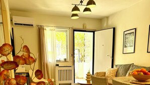 Ein Essbereich mit einem für zwei Personen gedecktem Tisch, einer Vase mit getrockneten Blumen und Blick ins Freie durch ein Fenster.