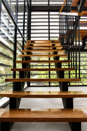 Un escalier moderne avec des marches en bois et des rampes en métal, menant à un niveau supérieur.