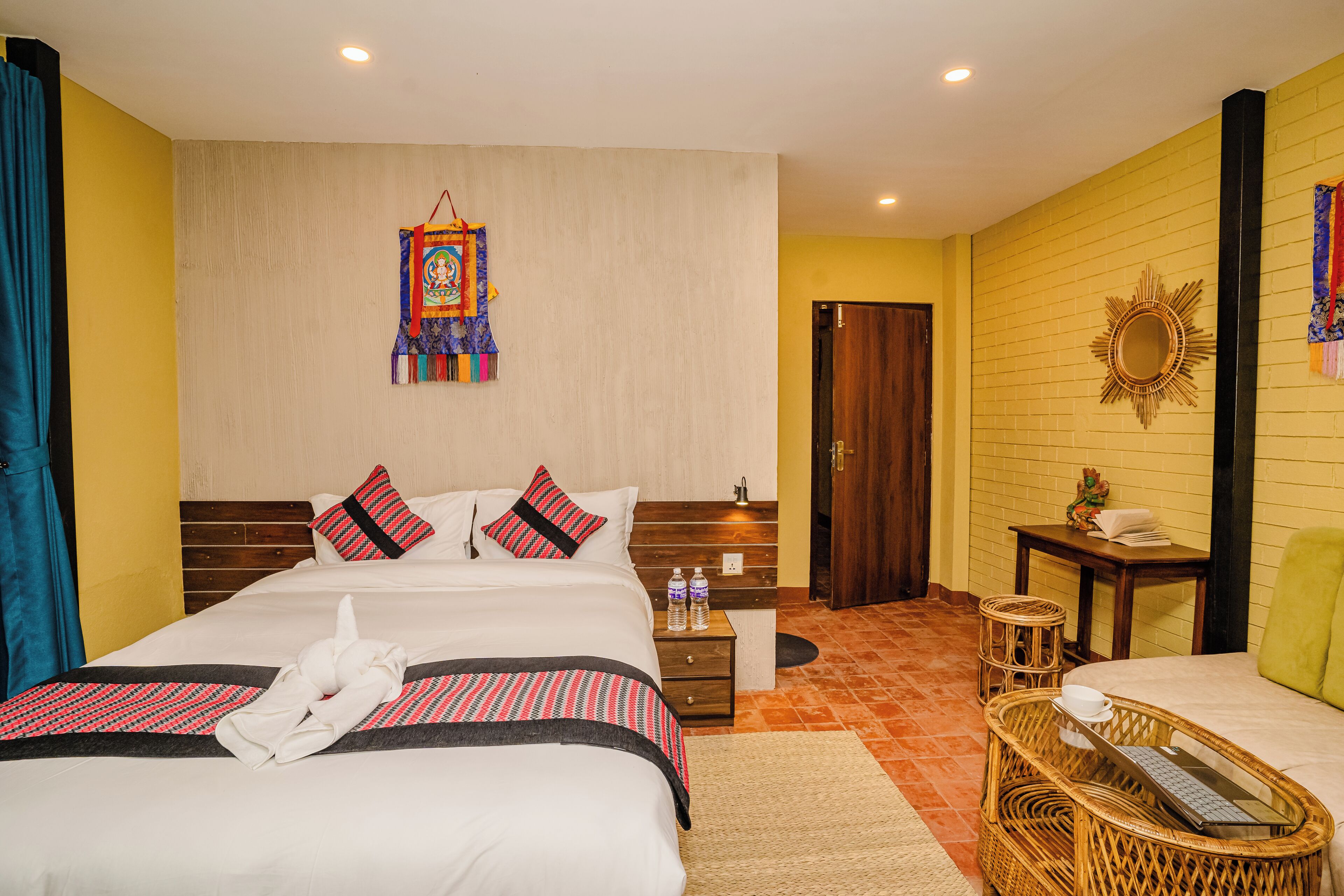 A hotel room with a large bed, a nightstand, a wicker side table, and a small desk.