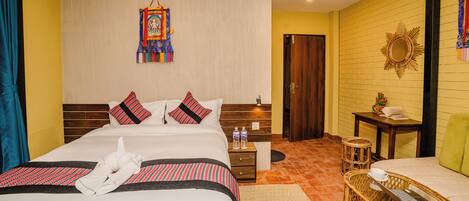 A hotel room with a large bed, a nightstand, a wicker side table, and a small desk.