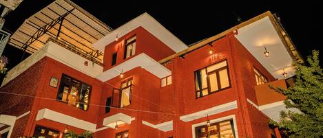 A multi-story building with a red brick facade, large windows, and a flat roof.
