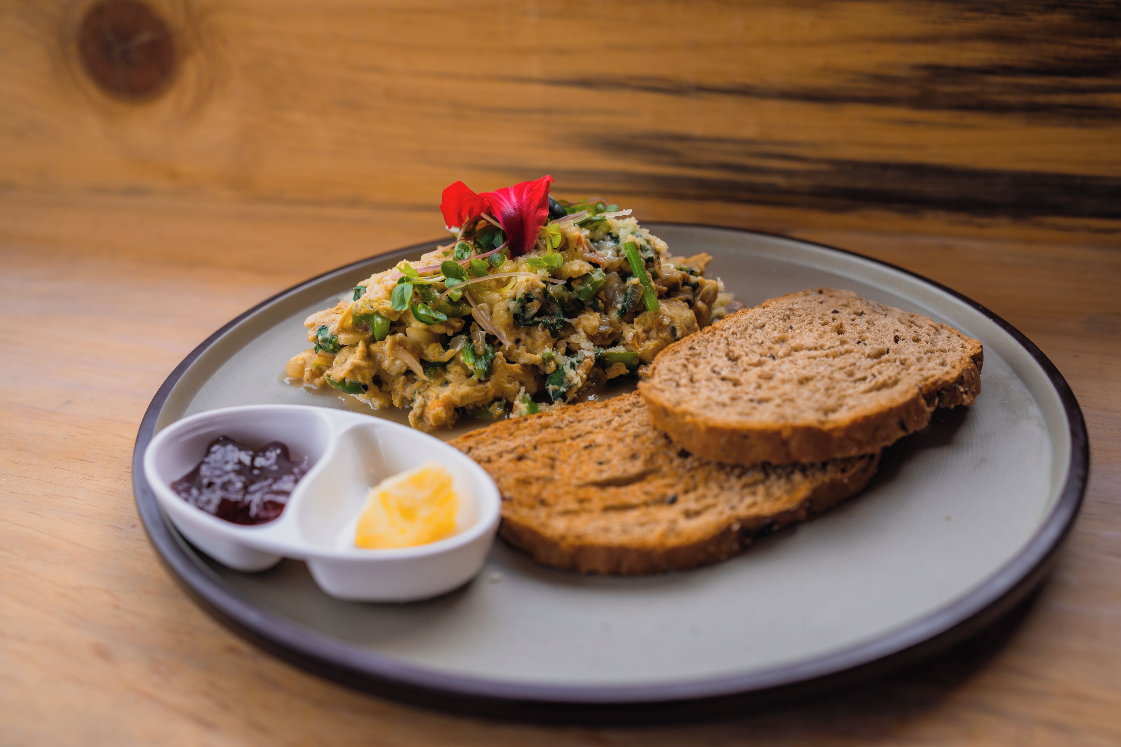 A plate with a salad, slices of bread, and two small bowls of condiments.