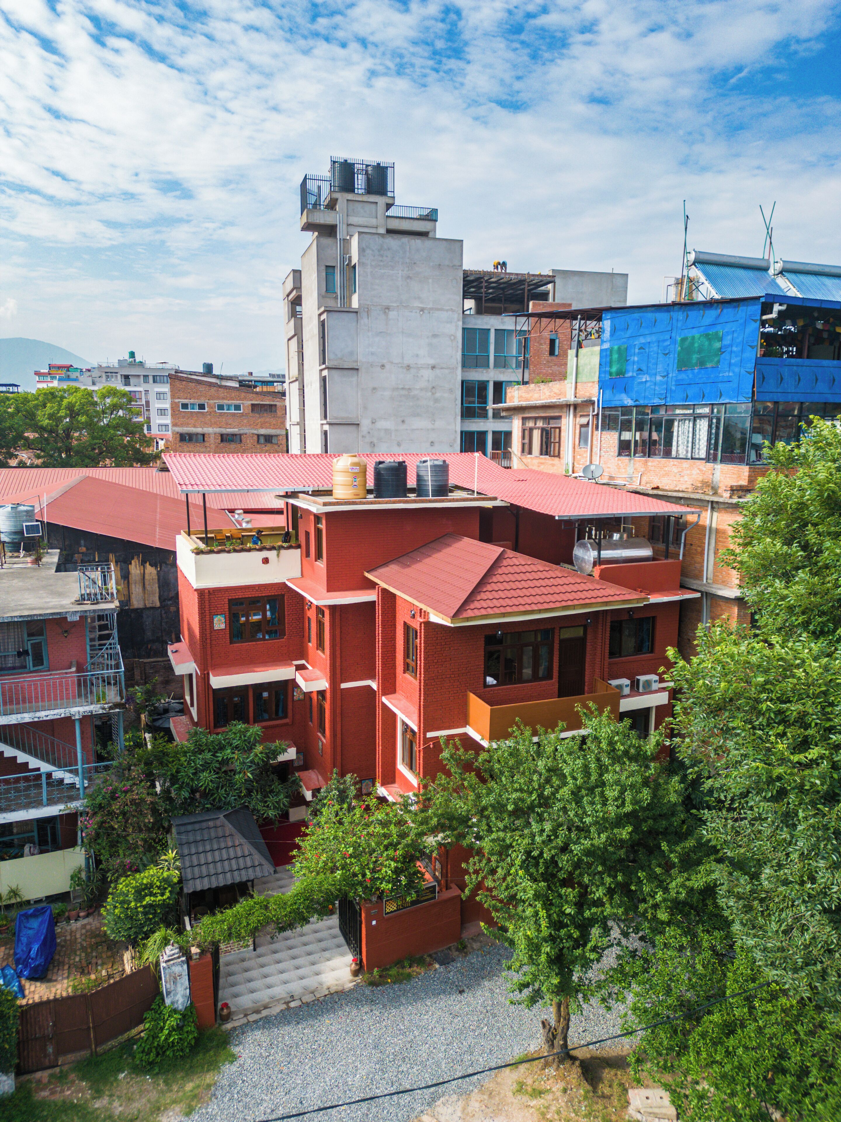Un edificio residencial de varios pisos con techo rojo, tanques de agua visibles en el techo y una antena parabólica.