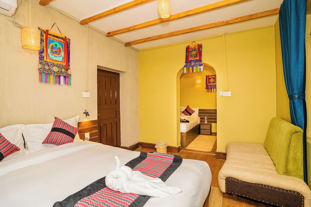 Habitación de hotel con una cama grande, un pequeño sofá, techo de madera y pared amarilla.
