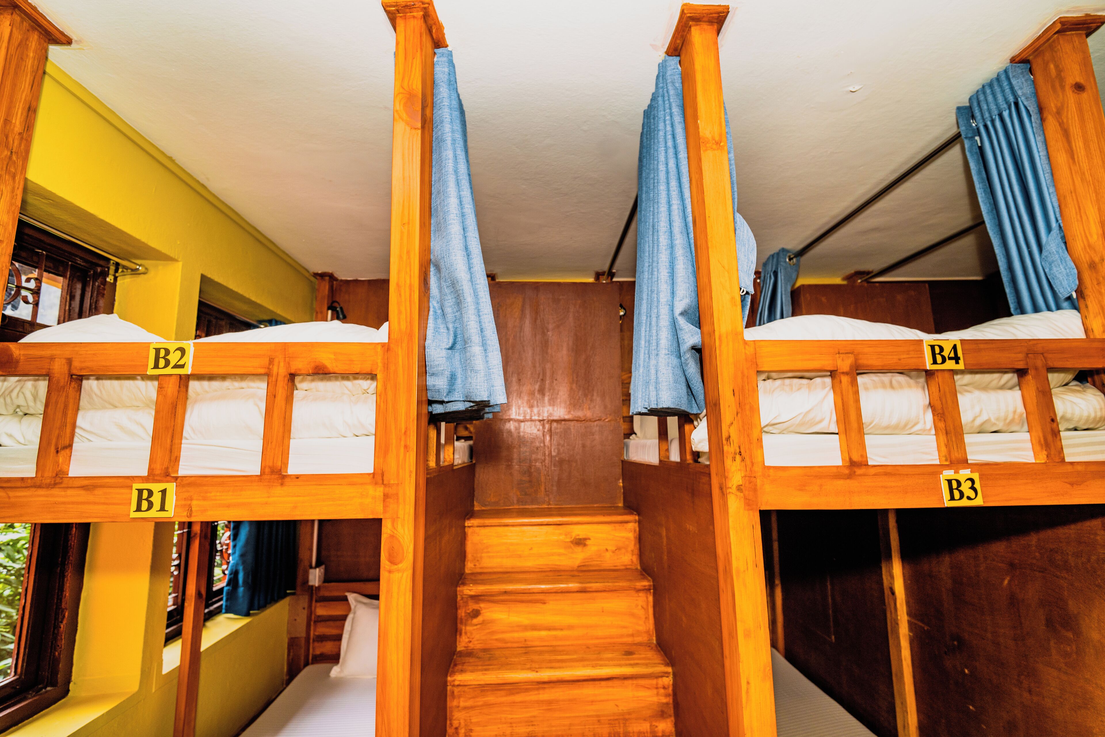 Habitación con literas, barandillas de madera y una escalera que lleva a un nivel inferior.