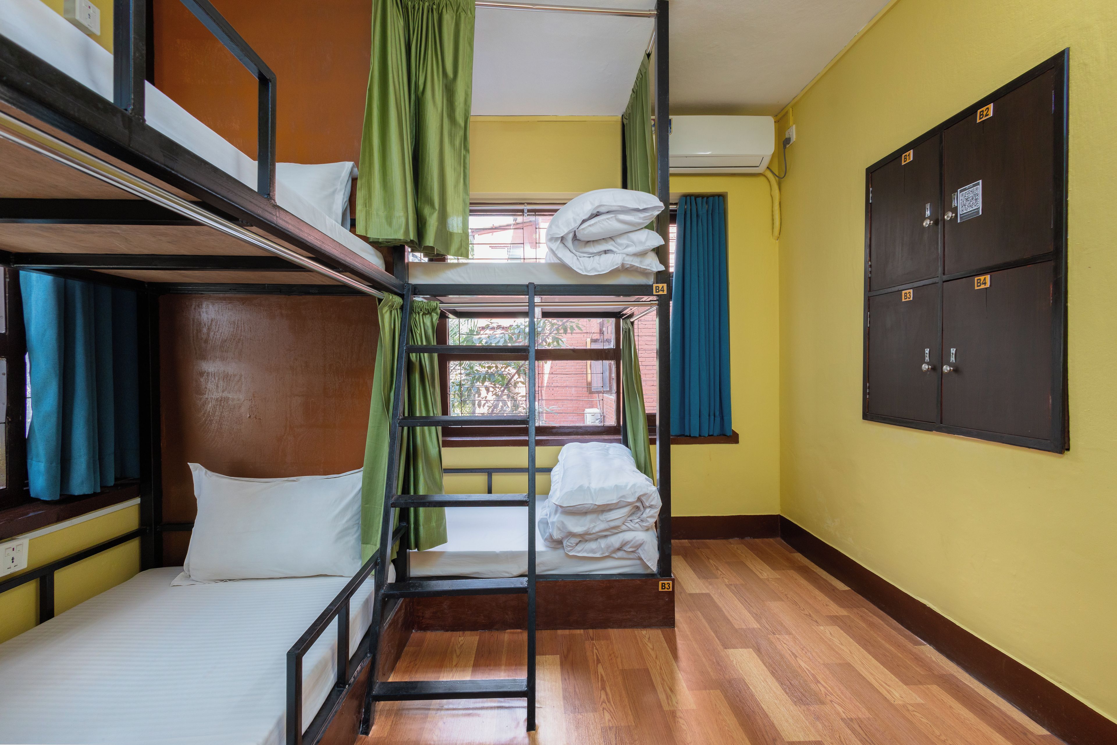 A bunk bed room with a window, a wardrobe, and a wooden floor.