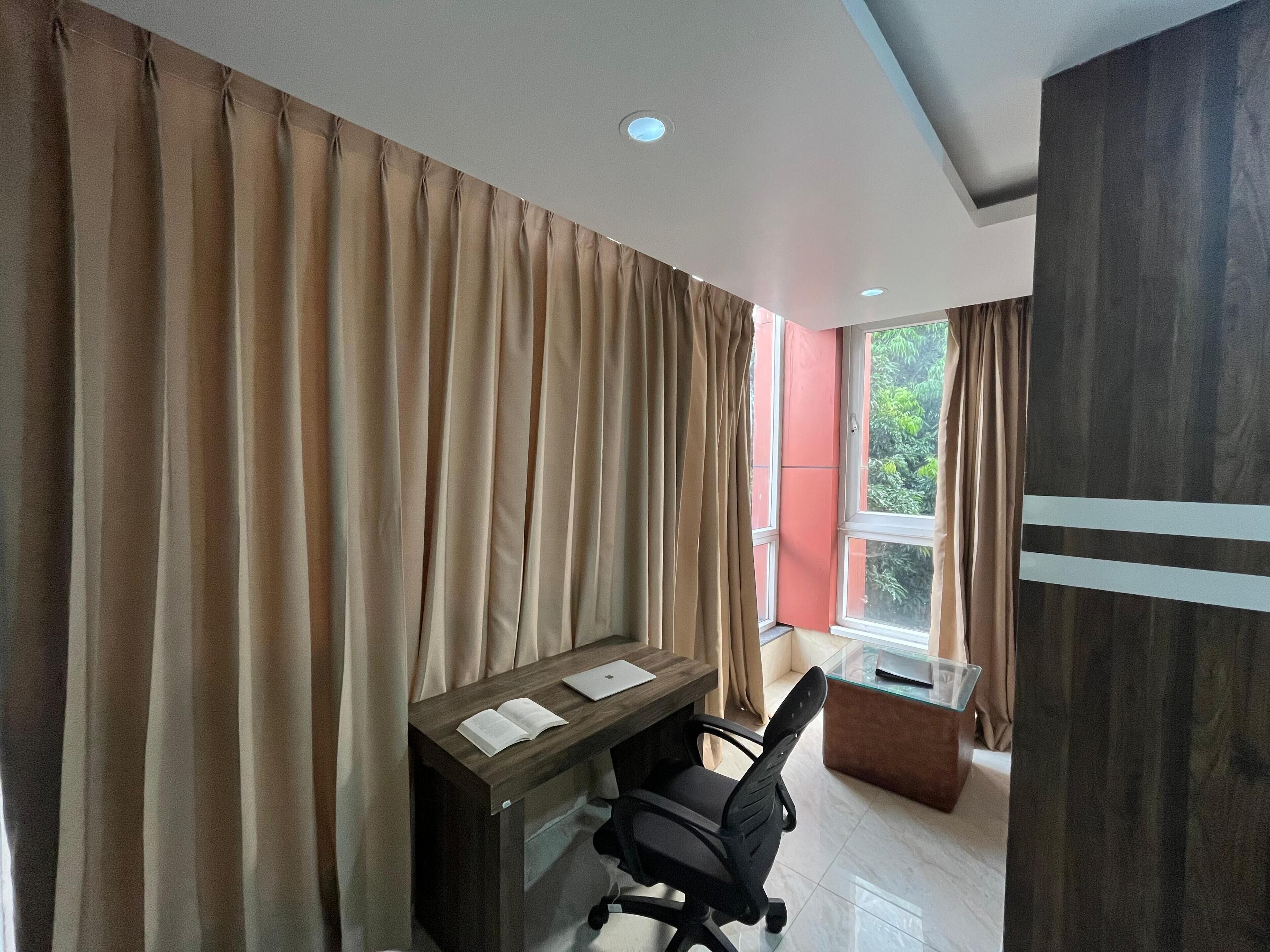 A modern office space with a desk, chair, and large windows.