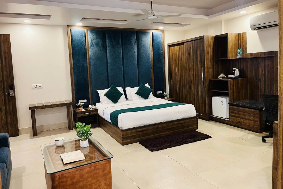 Une chambre moderne avec un grand lit, un bureau, une chaise, une armoire et un appareil de climatisation.