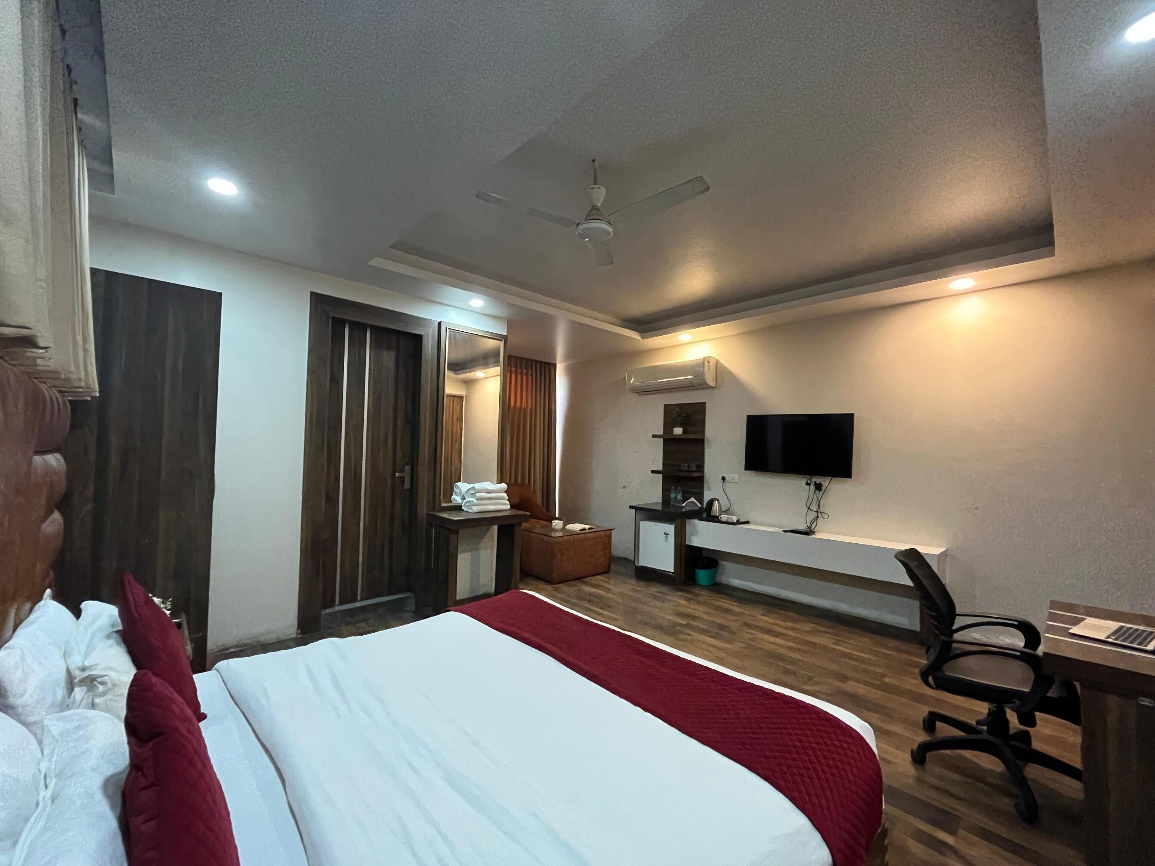 Une chambre d’hôtel équipée d’un lit, d’un bureau avec une chaise, d’une télévision et d’un ventilateur de plafond.