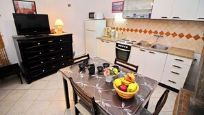 Una cucina compatta con un tavolo da pranzo, un frigorifero, un forno a microonde e un piano cottura.