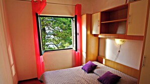 Una camera da letto con un letto, una finestra con tende, un comodino e un armadio.