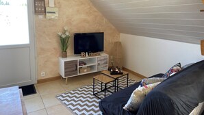 A cozy living room with a TV, a white cabinet, a coffee table, and a sofa. - Studio à la Campagne. Situé à 25 Minutes des Plages de Pénestin, Damgan (Missillac)
