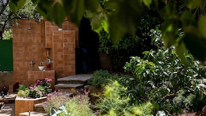 A brick-built outdoor shower area with a small sink and a step leading into a shaded area. - Garden Vista Apartment (Dubrovnik)