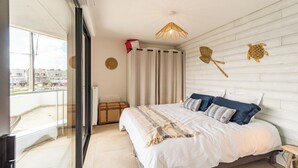 A bedroom with a large bed, a window with curtains, a ceiling light, and a wall-mounted decorative item.