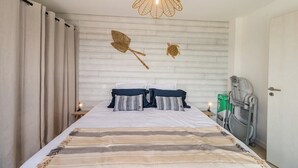 A bedroom with a bed, a wall-mounted light fixture, and a small bedside table with a lamp.