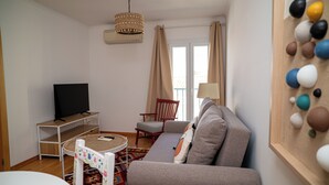 A living room with a sofa, a TV on a stand, a chair, and a lamp. - Turisalentejo  (Redondo)