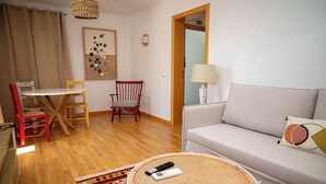 A living room with a sofa, a dining table with chairs, a lamp, and a remote control on a round table. - Turisalentejo  (Redondo)