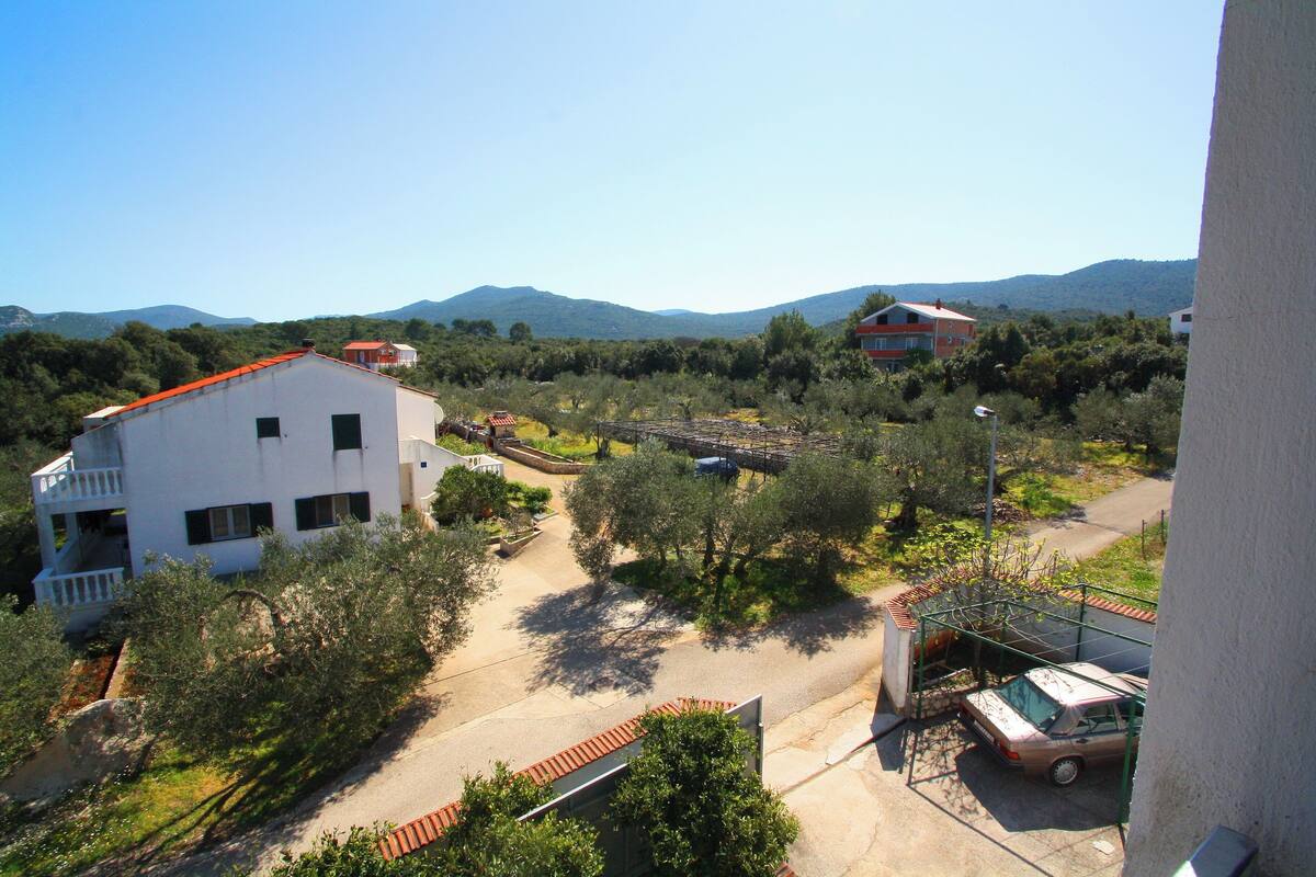 A white building with a red roof, surrounded by trees and a clear sky.
