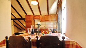 A dining area with a table set for two, wooden chairs, and a fruit bowl on the table. - Apartments Lemeš (Janjina)