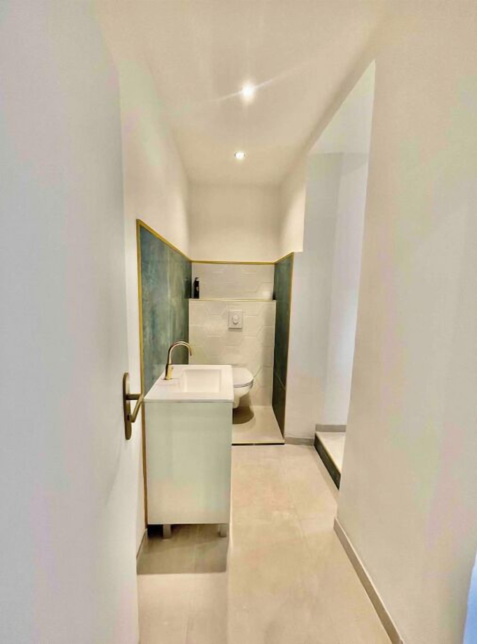 Une salle de bain moderne avec un lavabo blanc, des toilettes et un espace douche.