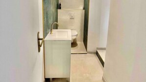 Un baño moderno con un lavamanos blanco, inodoro y zona de ducha.