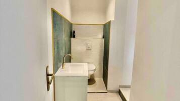 Une salle de bain moderne avec un lavabo blanc, des toilettes et un espace douche.