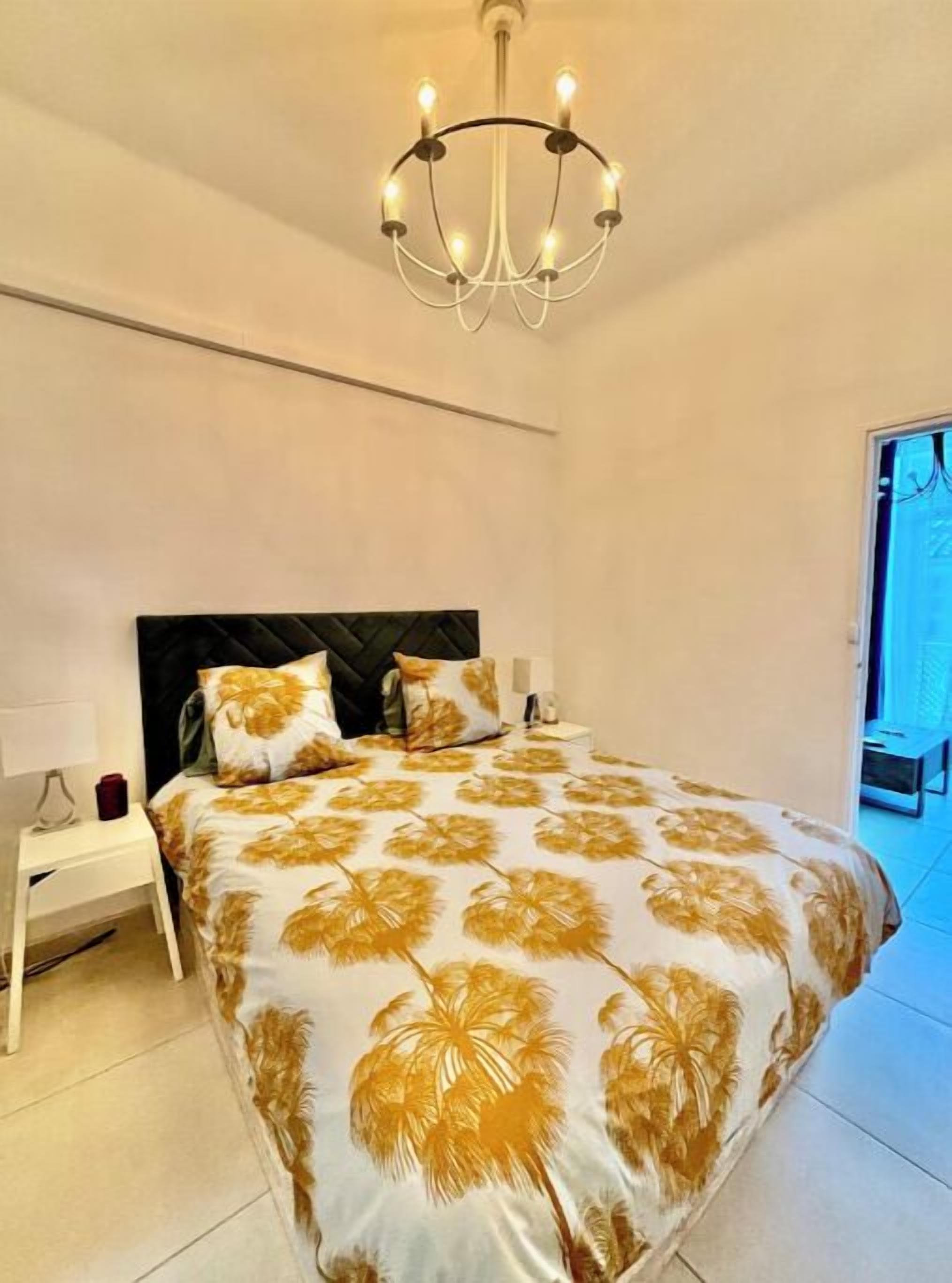 Une chambre à coucher avec un lit, une table de chevet, une lampe et un lustre.