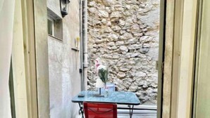 Un pequeño espacio al aire libre con una mesa, una silla, un muro de piedra y una lámpara.