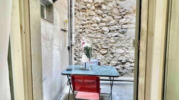 Un petit espace extérieur comprenant une table et une chaise, un mur en pierre et une lampe.