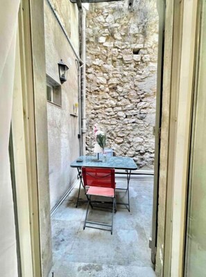 Un piccolo spazio all'aperto con un tavolo, una sedia, un muro in pietra e una lampada.