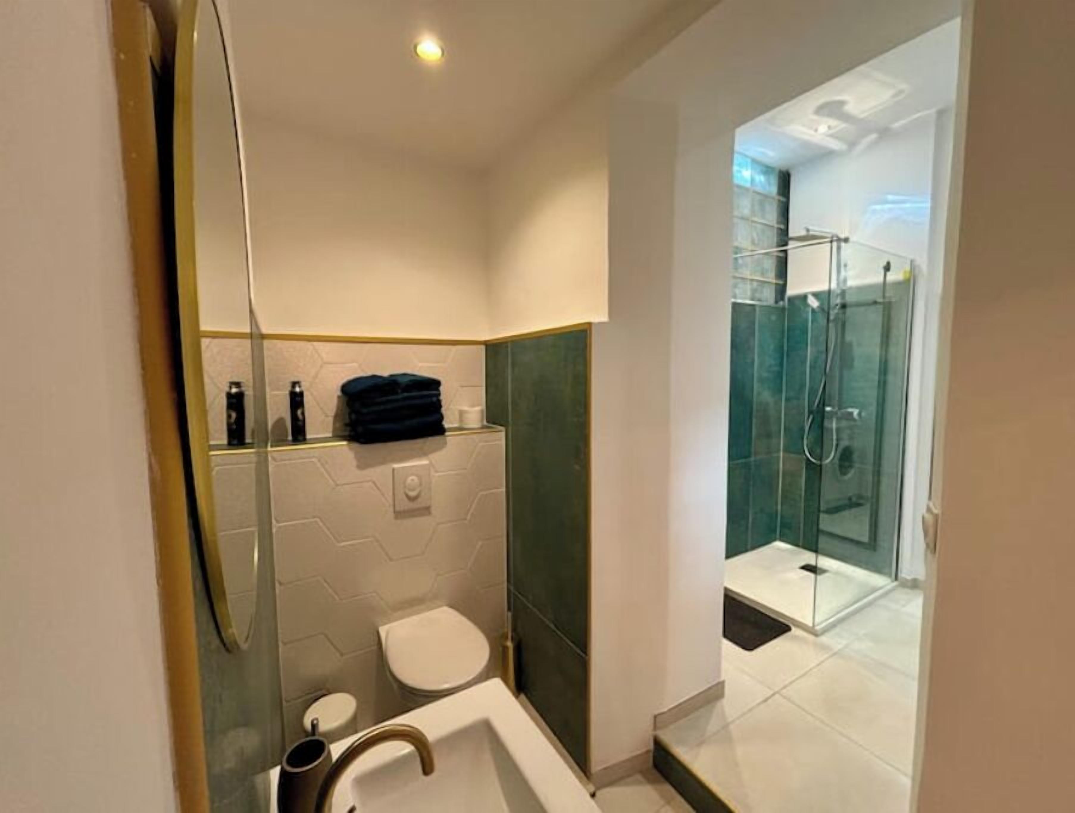 Une salle de bain moderne avec une douche à parois de verre, un lavabo blanc et des toilettes.