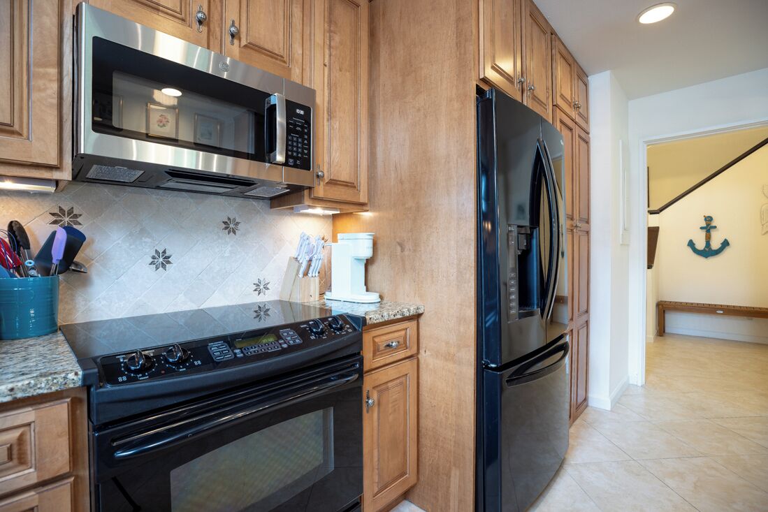 A kitchen with wooden cabinets, stainless steel appliances, and a granite countertop.