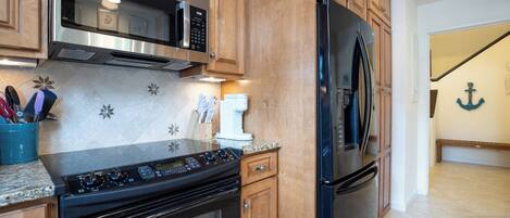 A kitchen with wooden cabinets, stainless steel appliances, and a granite countertop.