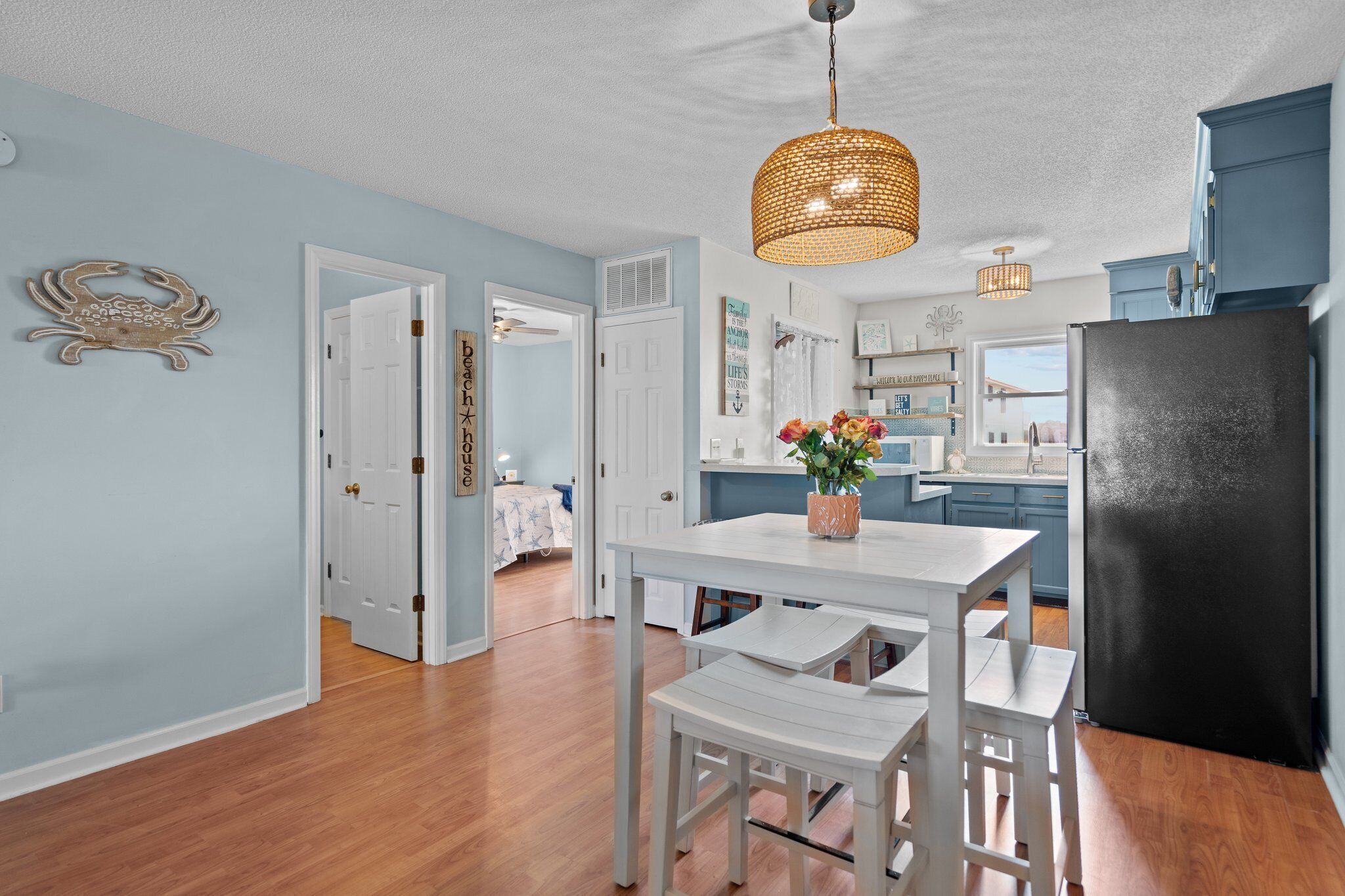 A kitchen with a black refrigerator, white cabinetry, and a hanging light fixture.