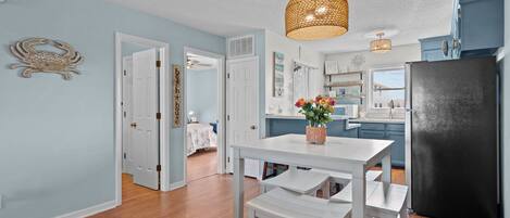 A kitchen with a black refrigerator, white cabinetry, and a hanging light fixture.
